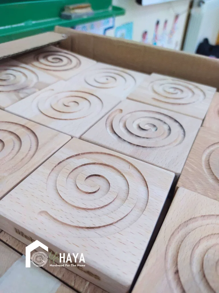 Primer plano de fichas cuadradas de madera de haya con grabado en espiral, usadas en el taller educativo del proyecto LIFE HAYA para los talleres educativos impartidos en colegios