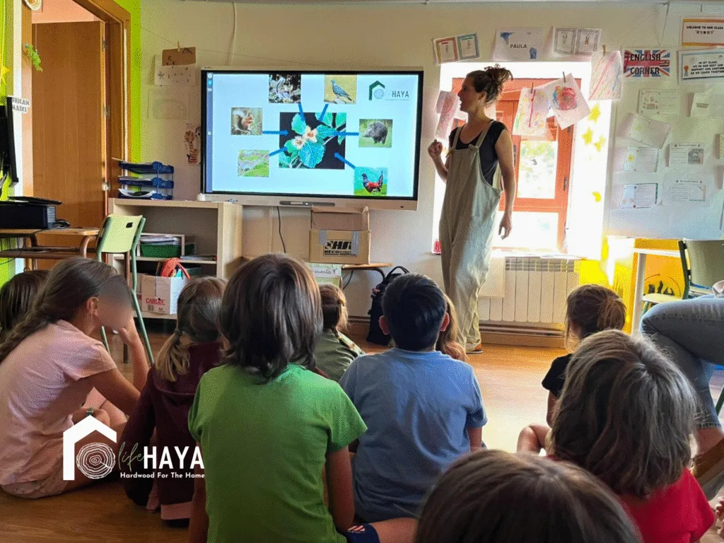 Silvia Goméz, de CESEFOR socio del proyecto Life Haya, muestra una diapositiva con fauna y flora del hayedo mientras los niños escuchan sentados en el aula.